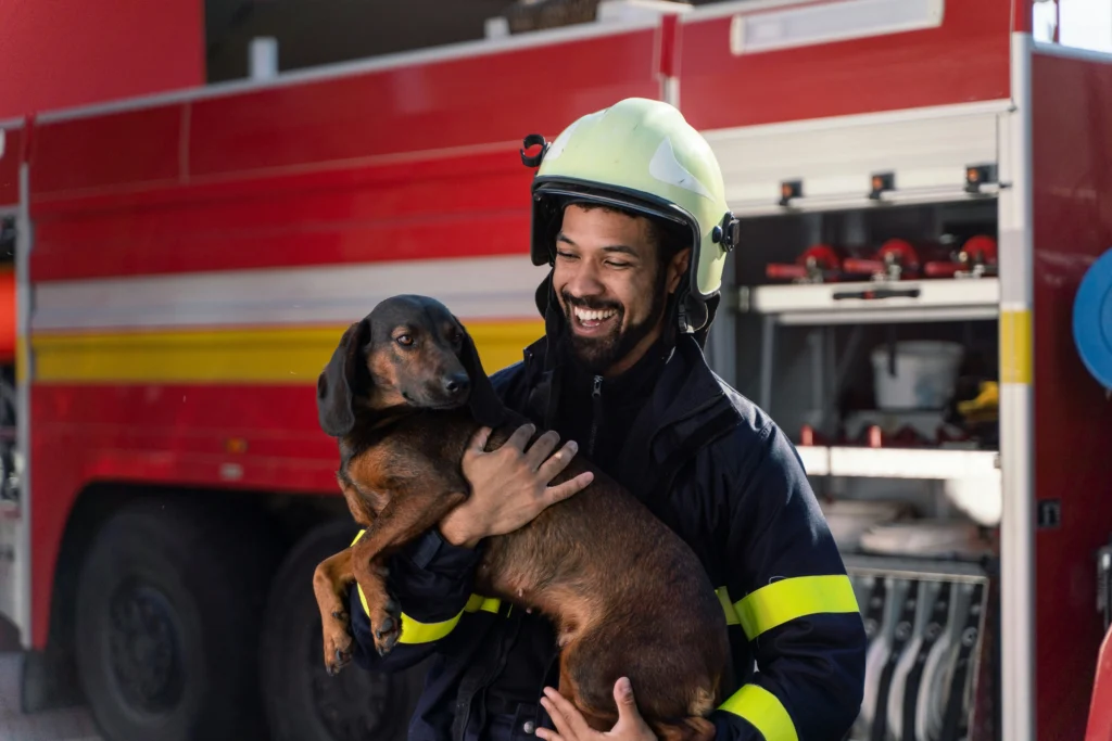 Firefighter holding dog and smiling after ear seeding for mental wellness